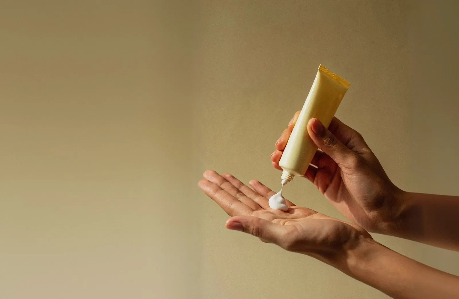 Cream being squeezed from a tube into an open palm