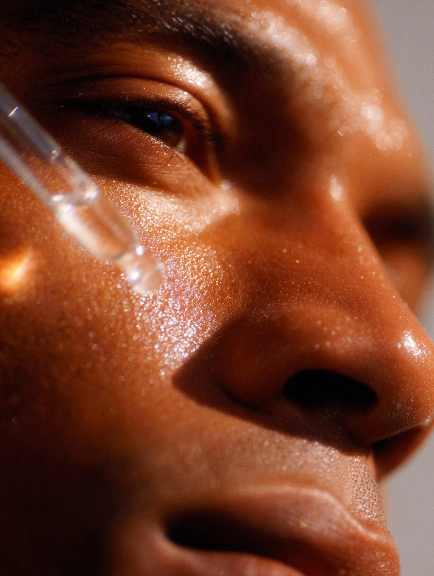 Serum dropper above glowing skin